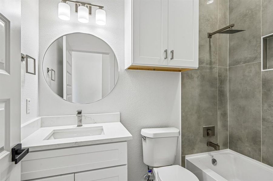 Contemporary bathroom featuring a white vanity with a quartz countertop, sleek chrome faucet, and circular mirror