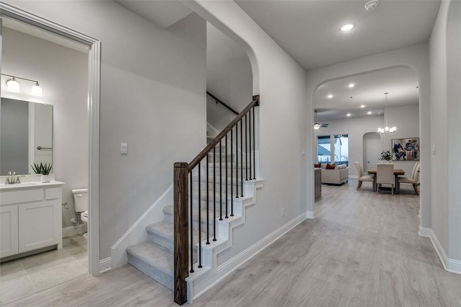 Staircase featuring sink, hardwood / wood-style floors, and ceiling fan with notable chandelier