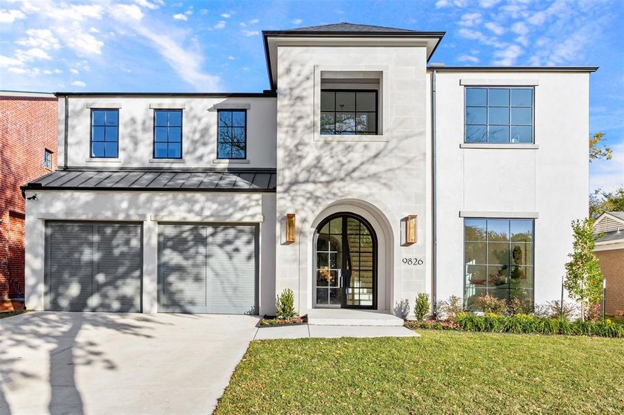 View of front of home featuring driveway, stucco siding, a standing seam roof, a front lawn, and a garage View of front of home featuring driveway, stucco siding, a standing seam roof, a front lawn, and a garage