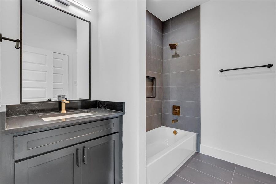 Bathroom with tile patterned flooring, vanity, and tiled shower / bath