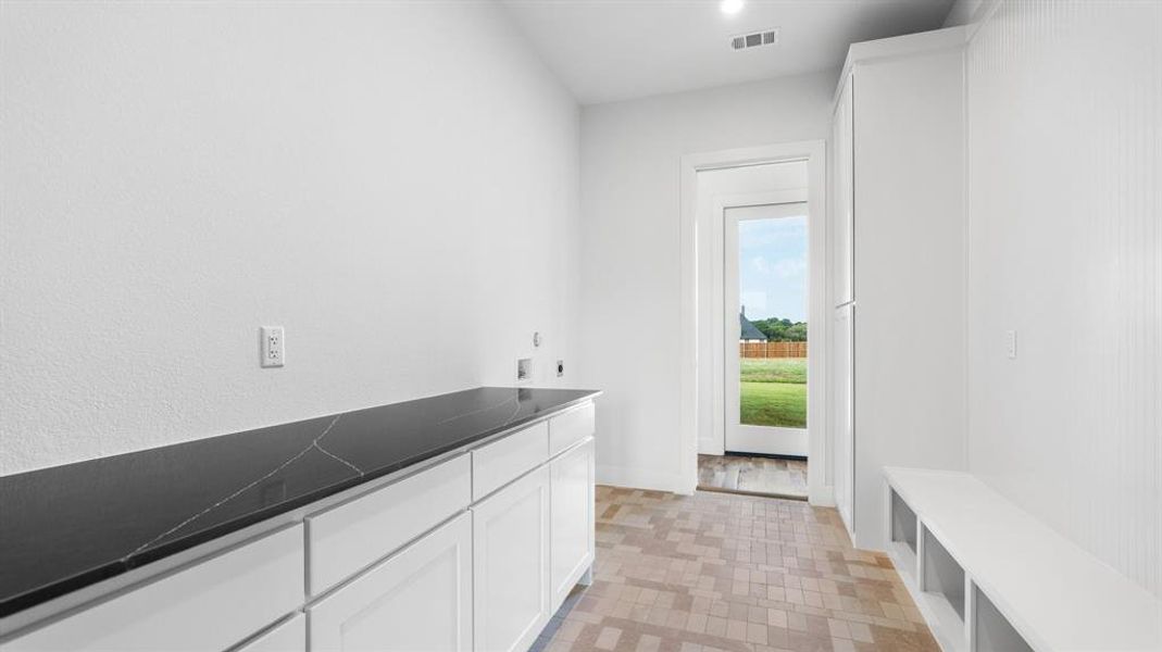 Laundry room with light hardwood / wood-style floors, hookup for an electric dryer, and cabinets