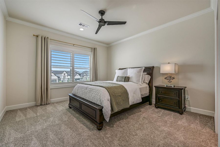 The third upstairs secondary bedroom offers another spacious retreat with plush carpet, crown molding, plantation shutters, a ceiling fan & a large closet.