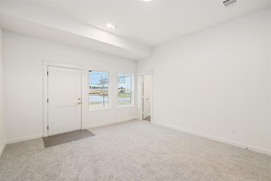 Carpeted spare room featuring visible vents and baseboards