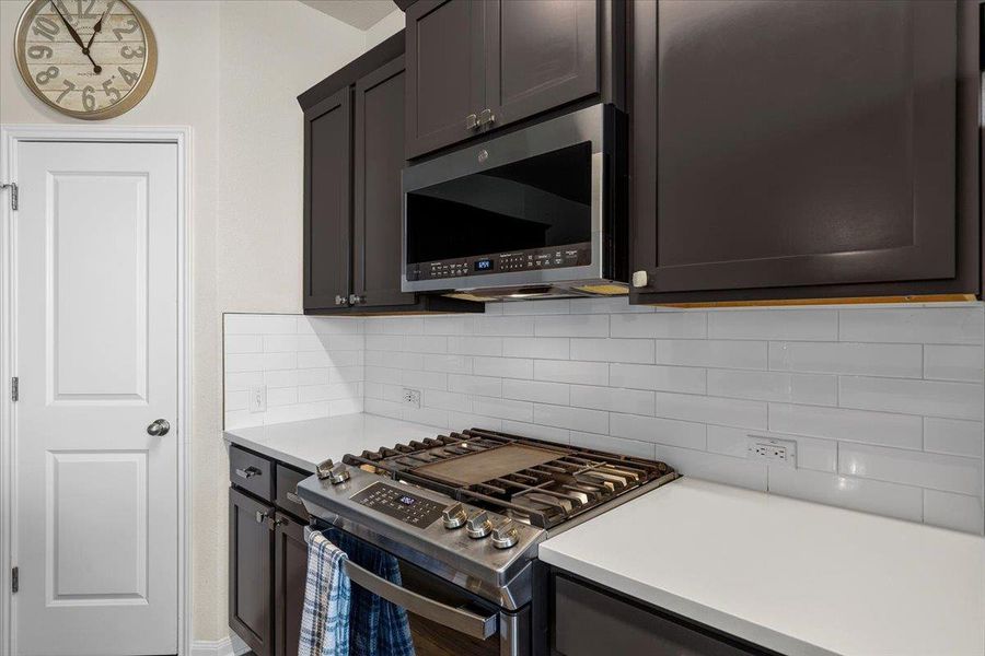 Dark cabinetry beautifully contrasts with a white subway tile backsplash and sleek solid surfaces.