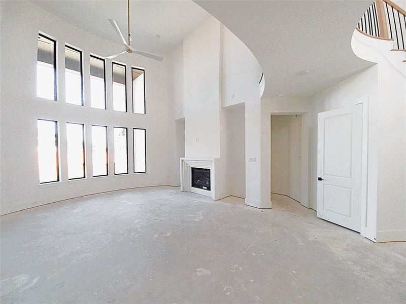 Another view of this impressive living room with high ceilings & gorgeous, stacked windows allowing lots of light in. Beautiful, engineered hardwood flooring is soon to come with a decorative gas fireplace to gather around.