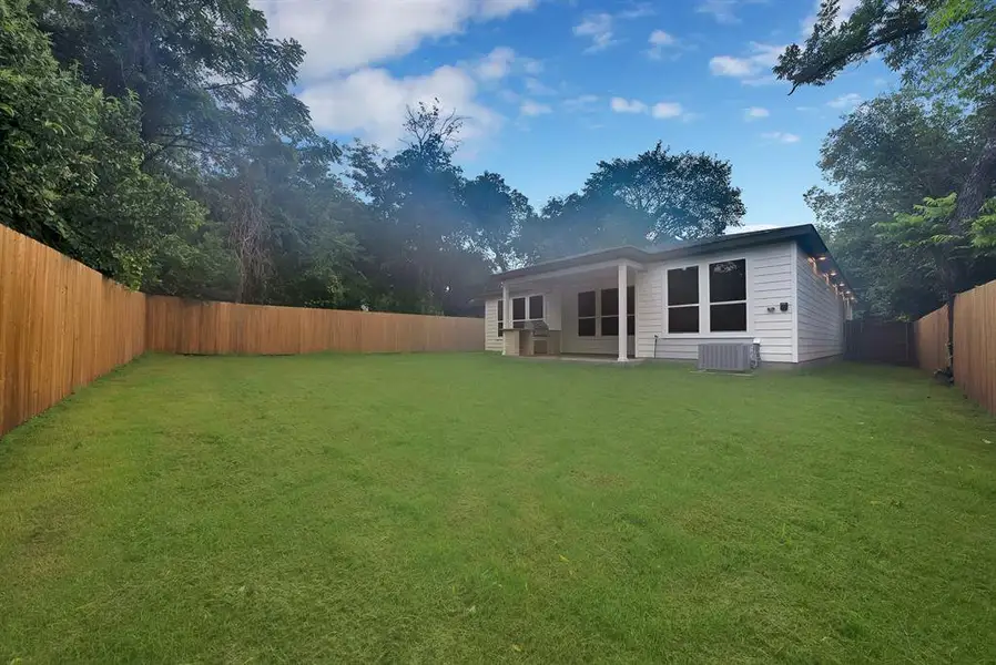 Expansive green lawn framed by a new wooden privacy fence and mature trees Expansive green lawn framed by a new wooden privacy fence and mature trees