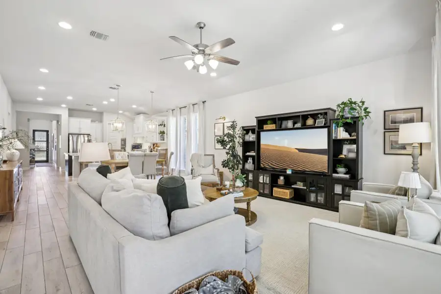 Living room featuring ceiling fan, light wood-type flooring, and hanging lights