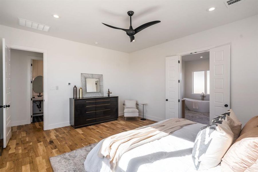 Bedroom with ceiling fan, connected bathroom, and light hardwood / wood-style floors