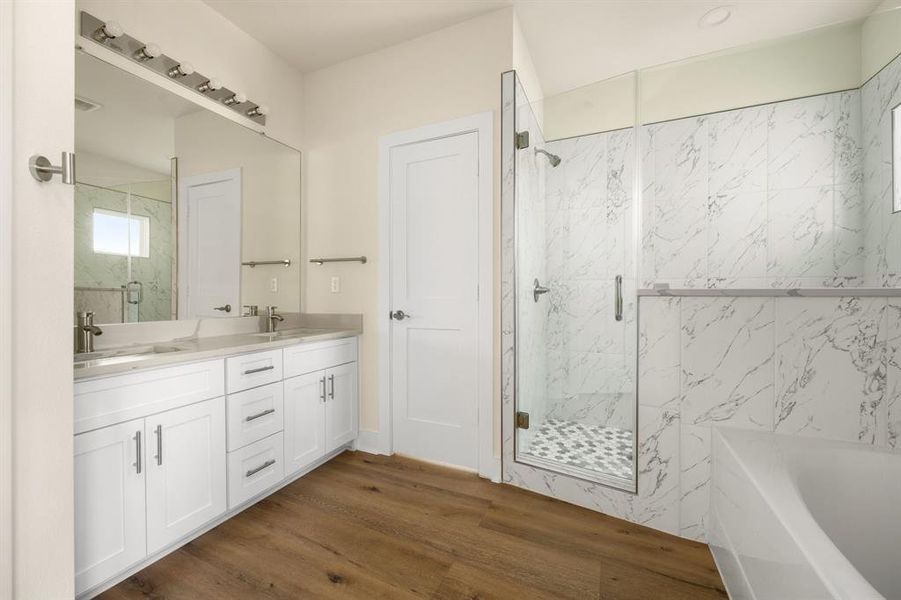 This primary bathroom is definitely move-in ready! Featuring a walk-in shower with tile surround, separate garden tub for soaking after a long day with custom tile detailing, white sleek cabinets with light countertops, high ceilings, custom paint, sleek and light modern finishes.