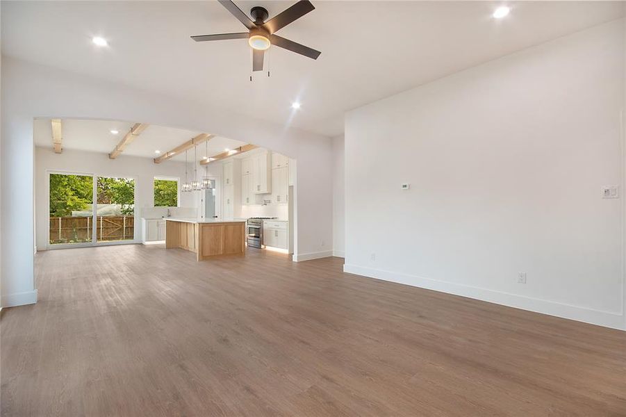Unfurnished living room with beamed ceiling, dark wood-style flooring, recessed lighting, a ceiling fan, and a chandelier