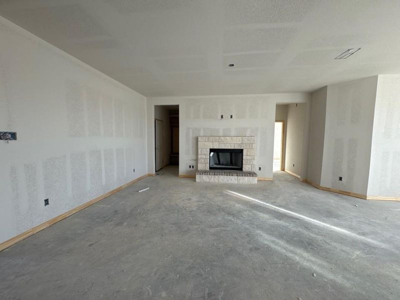 Unfurnished living room with a fireplace and unfinished concrete flooring Unfurnished living room with a fireplace and unfinished concrete flooring