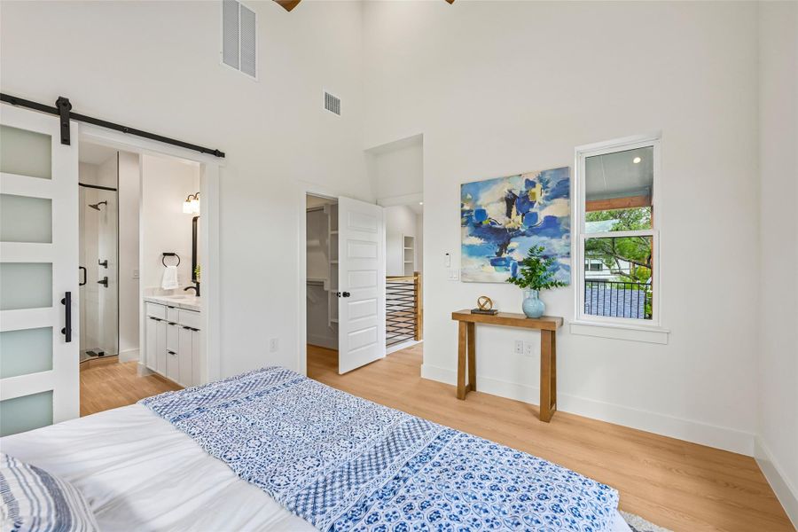 A peaceful retreat awaits, featuring vaulted ceilings and a private en-suite bathroom accessible via a modern barn door.
