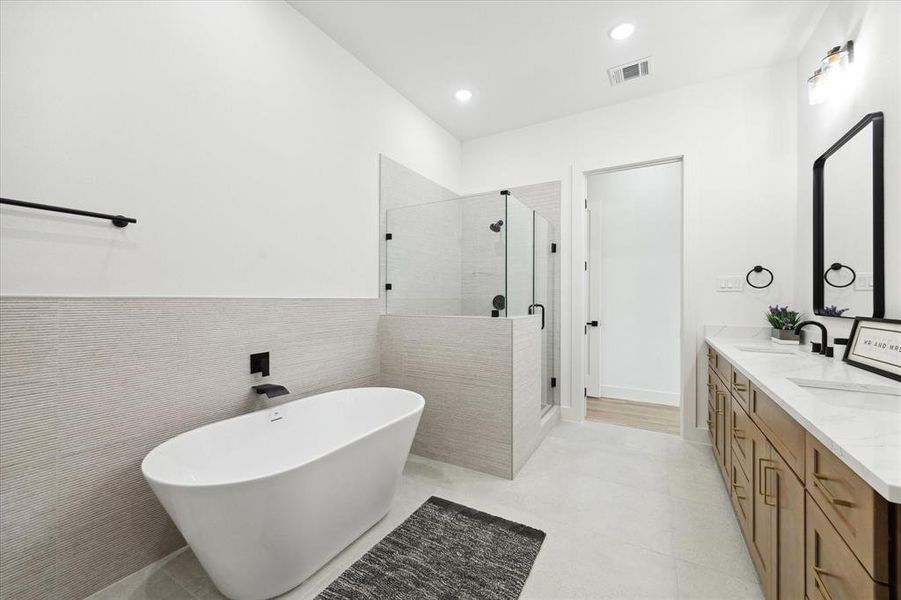 Primary bathroom boasts his and hers vanities, a private water closet, a glass-enclosed walk in shower, with an incredible soaking tub.