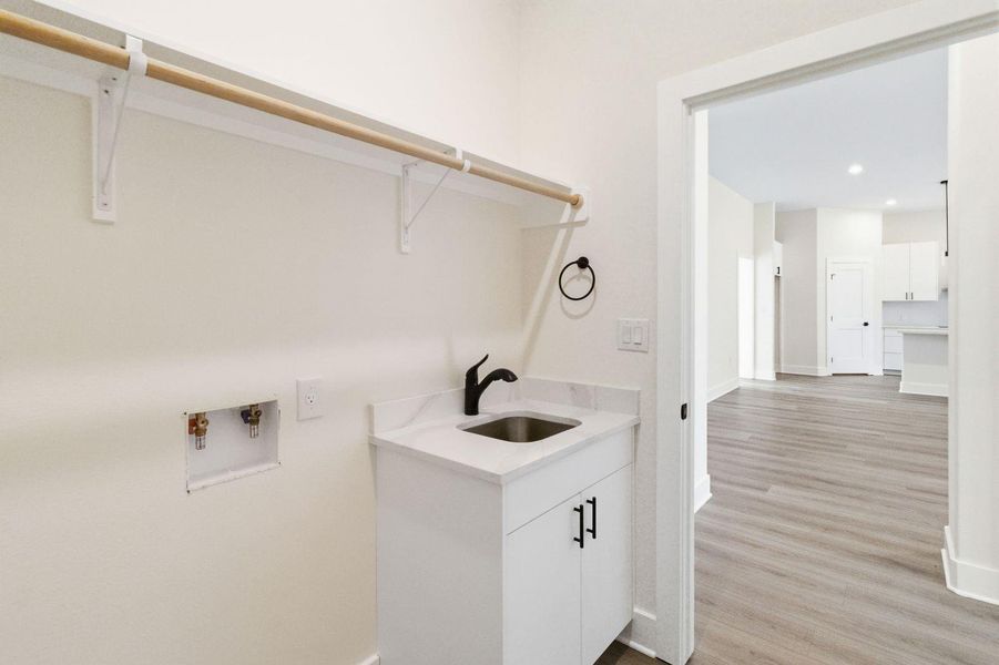A dedicated laundry space boasts a utility sink and hanging rod, simplifying household tasks. A dedicated laundry space boasts a utility sink and hanging rod, simplifying household tasks.