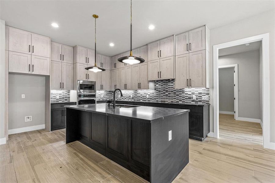 Kitchen with sink, light wood-type flooring, stainless steel appliances, and decorative backsplash