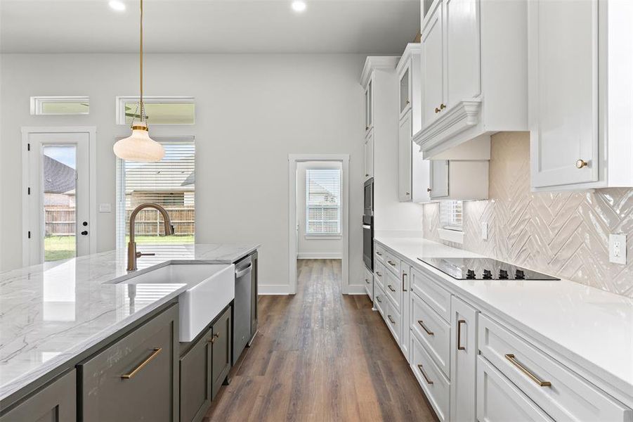 Kitchen featuring white cabinets, decorative light fixtures, light stone countertops, backsplash, and dark wood-style flooring Kitchen featuring white cabinets, decorative light fixtures, light stone countertops, backsplash, and dark wood-style flooring
