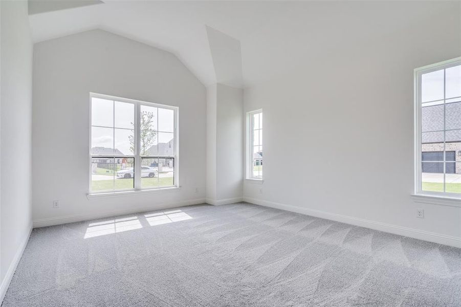 Carpeted empty room featuring vaulted ceiling