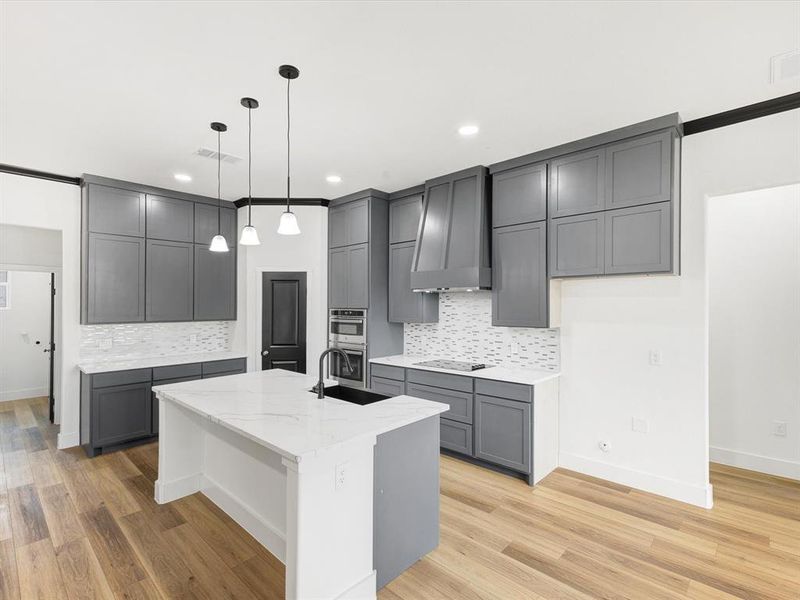 Kitchen featuring gray cabinets, light stone countertops, pendant lighting, a center island with sink, and a kitchen breakfast bar Kitchen featuring gray cabinets, light stone countertops, pendant lighting, a center island with sink, and a kitchen breakfast bar