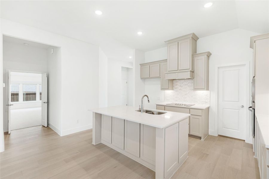 Kitchen with center island, sink, gray cabinets, white countertops, and light wood floors