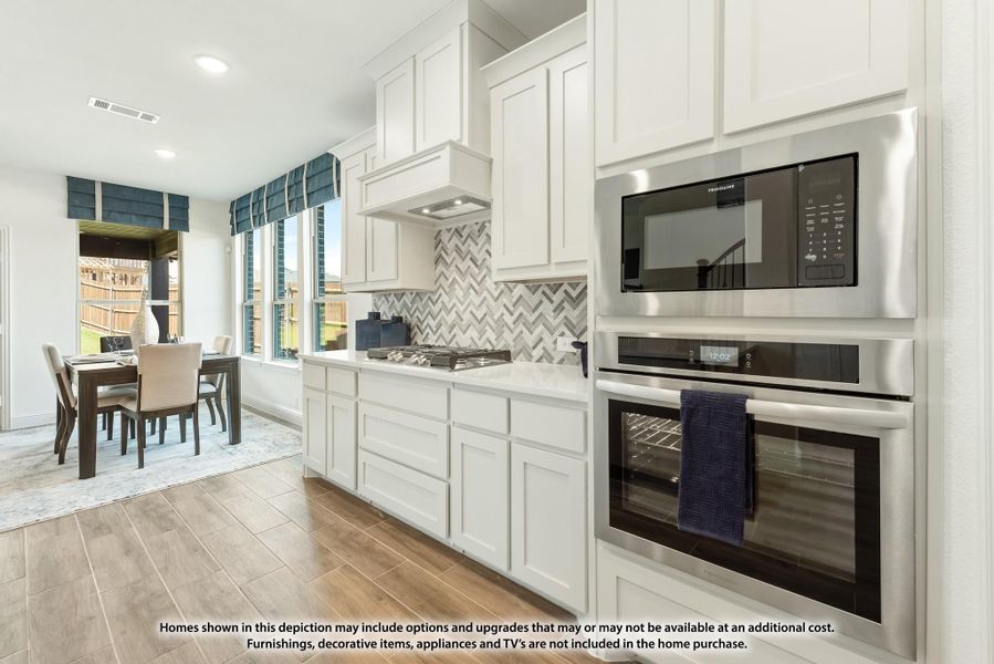 Kitchen with white cabinets, herringbone tile backsplash, stainless steel wall oven and microwave, open to dining area. Kitchen with white cabinets, herringbone tile backsplash, stainless steel wall oven and microwave, open to dining area.