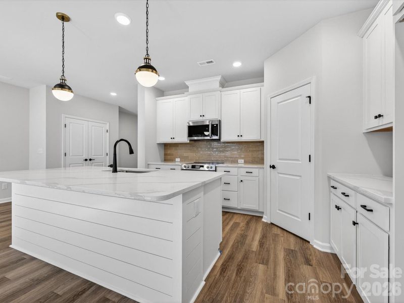 Open kitchen features 42" cabinets with soft close doors & drawers with large kitchen shiplap Island, quartz countertops, single bowl SS sink, tiled backsplash, Frigidaire gallery range appliances which are vented to outside of the home. Large walk-in pantry with solid shelving.