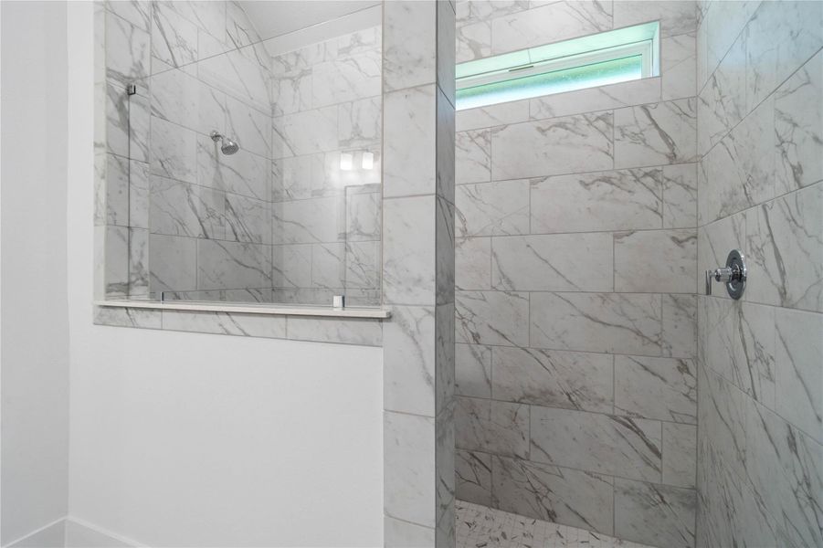 The spa-like primary bathroom boasts an oversized walk-in shower wrapped in timeless marble-look tile from floor to ceiling. The spa-like primary bathroom boasts an oversized walk-in shower wrapped in timeless marble-look tile from floor to ceiling.
