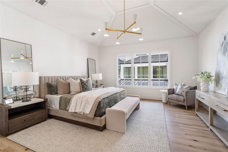 The primary bedroom is fit for royalty. Vaulted, 12-foot ceilings highlight the Aerin Albertine Chandelier. The triad of windows brings in natural light, and the hardwoods continue here for maximum luxury. A king bed and supplemental furniture fit with ease.