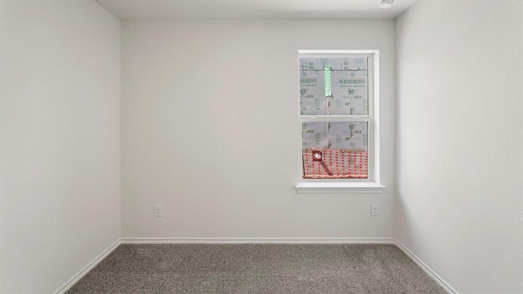 Bright interior room with textured walls, white baseboards, and gray carpet