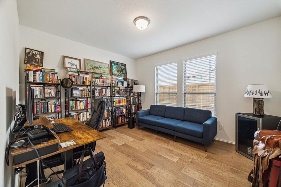 A dedicated office at the front of the home features engineered hardwood flooring and dual windows that bathe the room in natural light.