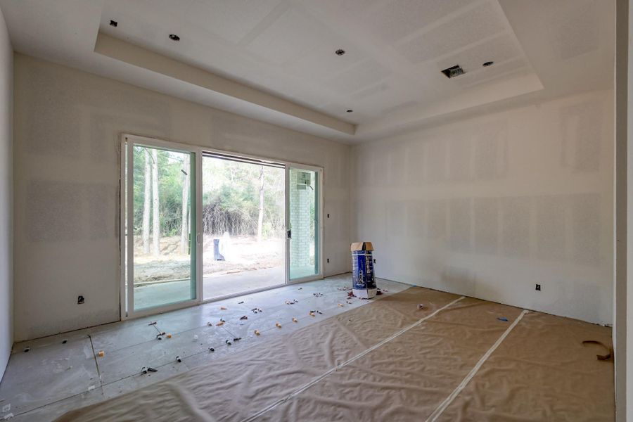 A serene primary retreat with soft, earthy tones and tranquil views, designed to feel both luxurious and grounding with sliding glass doors that open to an owner's exclusive, private back porch.