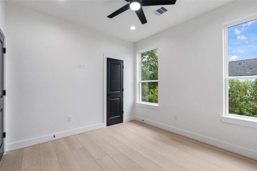 Bedroom view with black doors and light wood flooring for modern contrast. Bedroom view with black doors and light wood flooring for modern contrast.