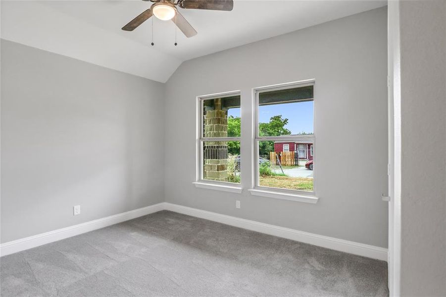 Carpeted spare room featuring lofted ceiling and ceiling fan