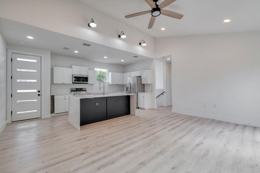 A contemporary open-concept space features light wood-look flooring and a functional kitchen with a contrasting island. A contemporary open-concept space features light wood-look flooring and a functional kitchen with a contrasting island.