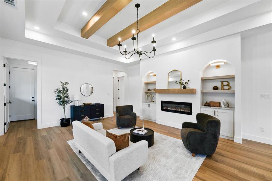 Spacious living area featuring high ceilings with exposed wood beams, recessed lighting, and a modern fireplace with a wood-finish mantel