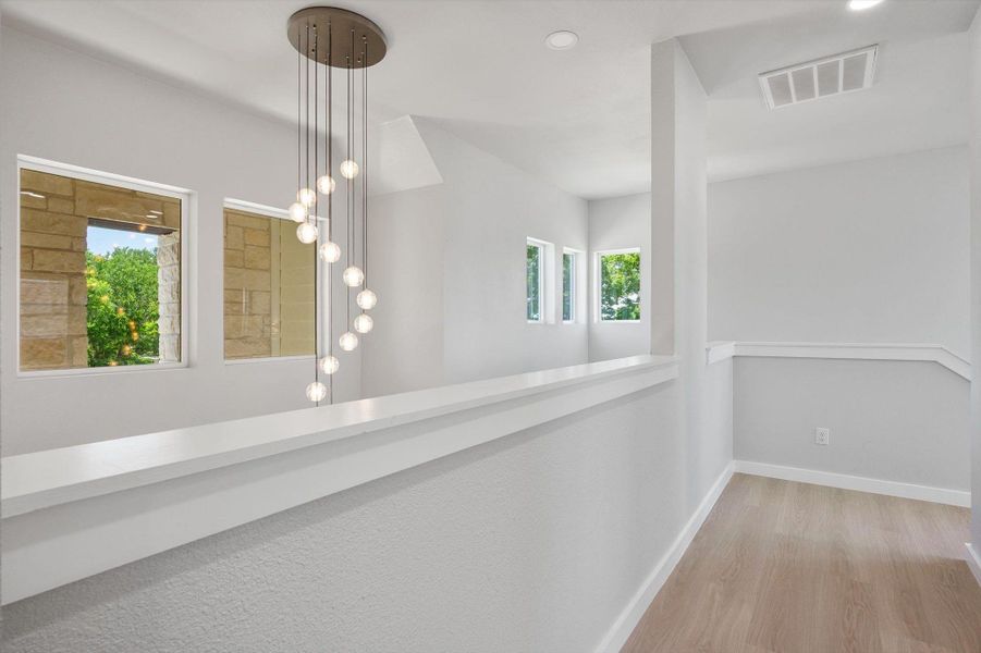 Modern lighting illuminates the open-concept hallway, featuring durable hardwood flooring and abundant natural light.