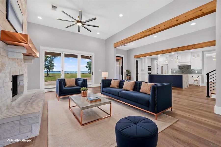 Magnificent open concept living room highlighted by soaring ceilings, timber accent beams, a striking stone fireplace with custom timber mantle, and an expansive view of the lake. Magnificent open concept living room highlighted by soaring ceilings, timber accent beams, a striking stone fireplace with custom timber mantle, and an expansive view of the lake.