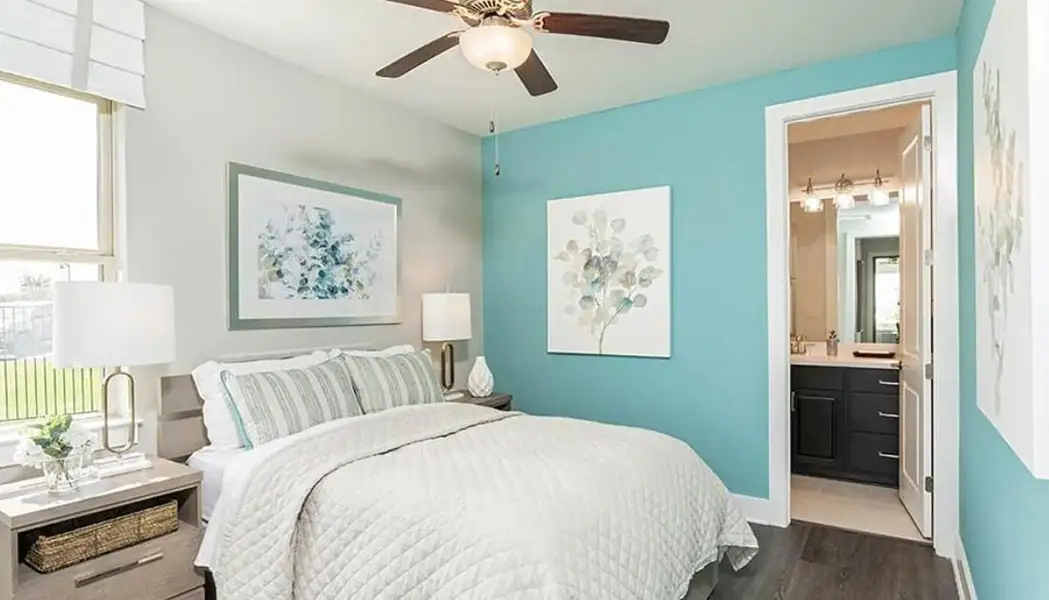 Bedroom with dark wood-style floors, multiple windows, a ceiling fan, and connected bathroom