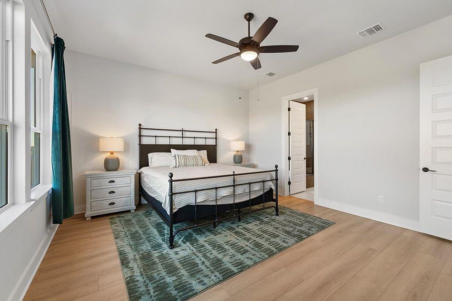 Gleaming hardwood floors and tall windows anchor this peaceful, sunlit bedroom retreat.