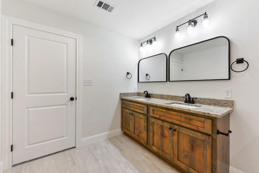 Jack 'n Jill  Full bathroom featuring wood plank tile floors, visible vents, baseboards, and a sink