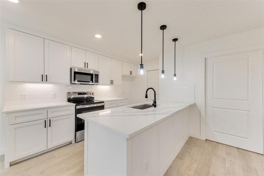 Kitchen with white cabinetry, sink, kitchen peninsula, and appliances with stainless steel finishes