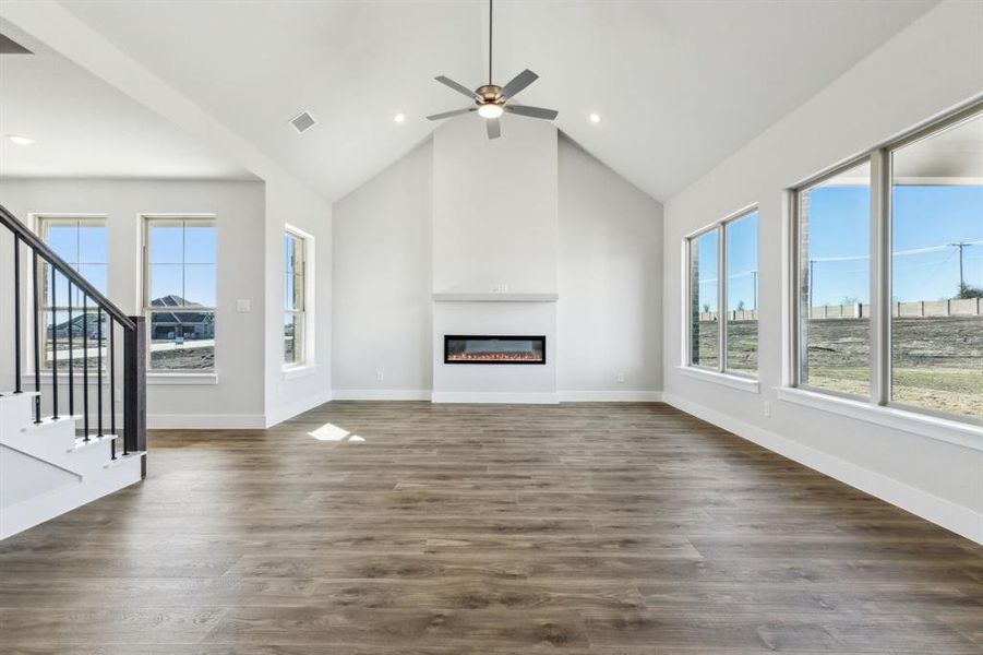 Unfurnished living room featuring ceiling fan, dark wood-type flooring, and high vaulted ceiling
