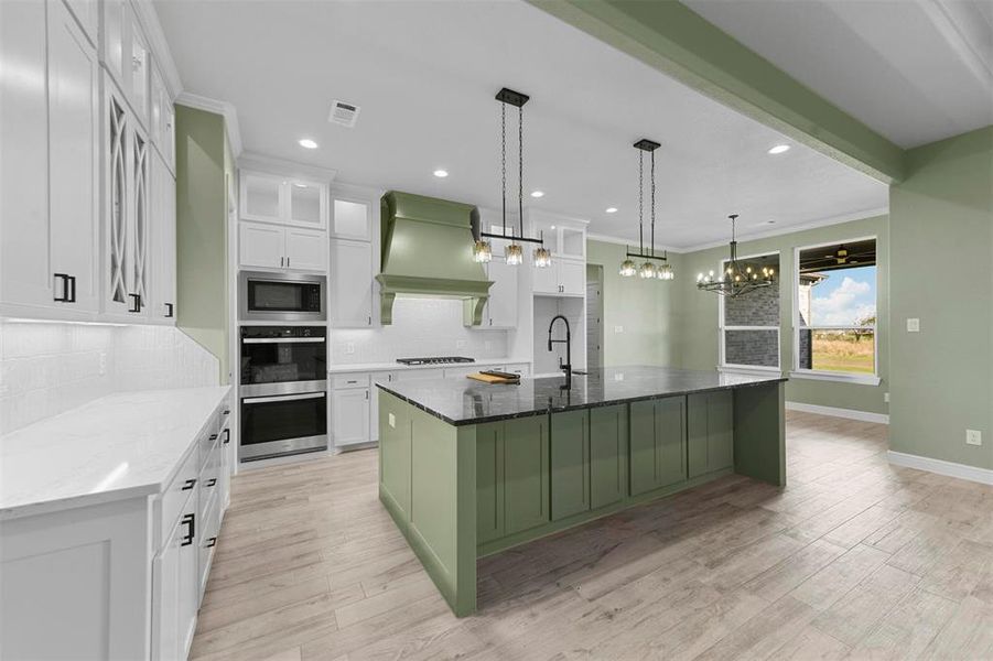 Kitchen featuring a center island with sink, white cabinetry, dark stone countertops, and custom exhaust hood