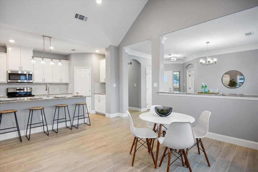 Dining area with sink, lofted ceiling, and ornamental molding