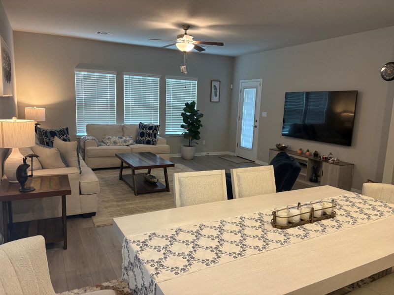 An inviting open-concept living and dining area features abundant natural light and rich wood flooring.