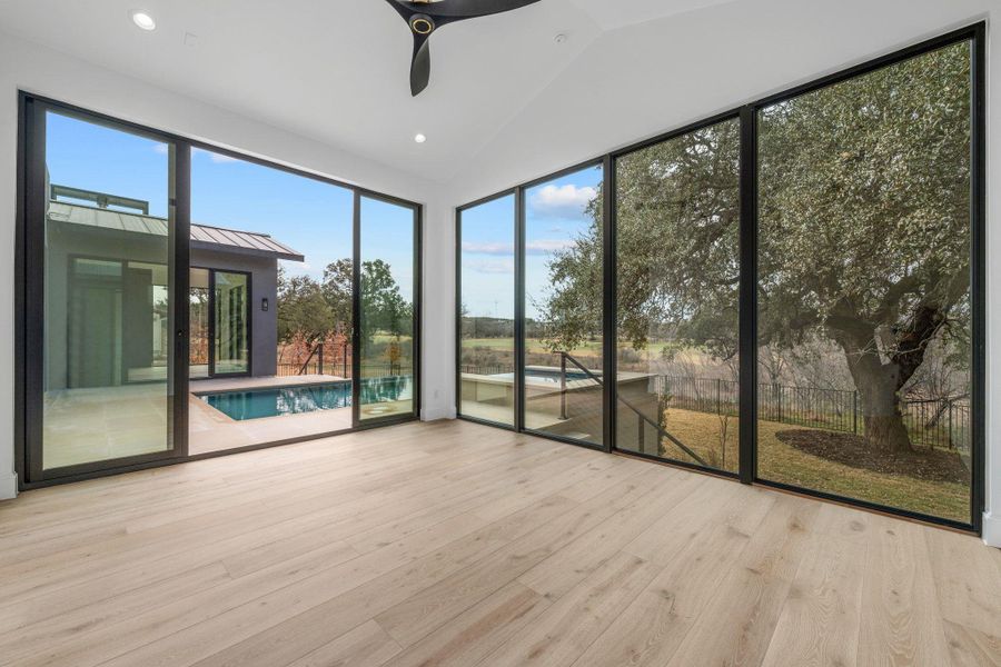 Unfurnished sunroom with lofted ceiling, recessed lighting, and wood finished floors