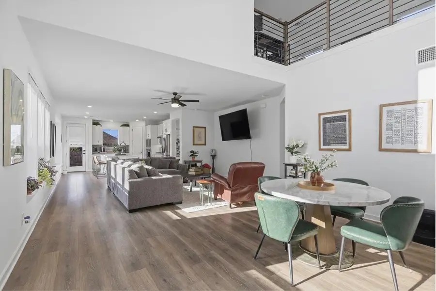 Living room with light wood-style floors, recessed lighting, a ceiling fan, and a high ceiling