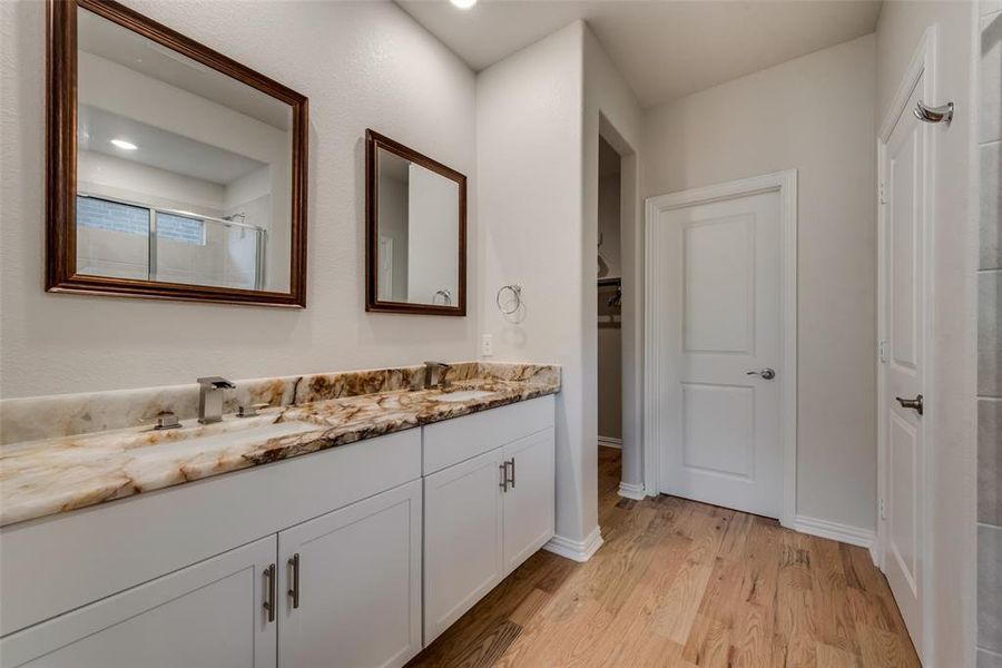 Master bathroom featuring exotic granite countertop, huge double sink vanity with designer LED faucets, framed vanity mirrors and hardwood flooring