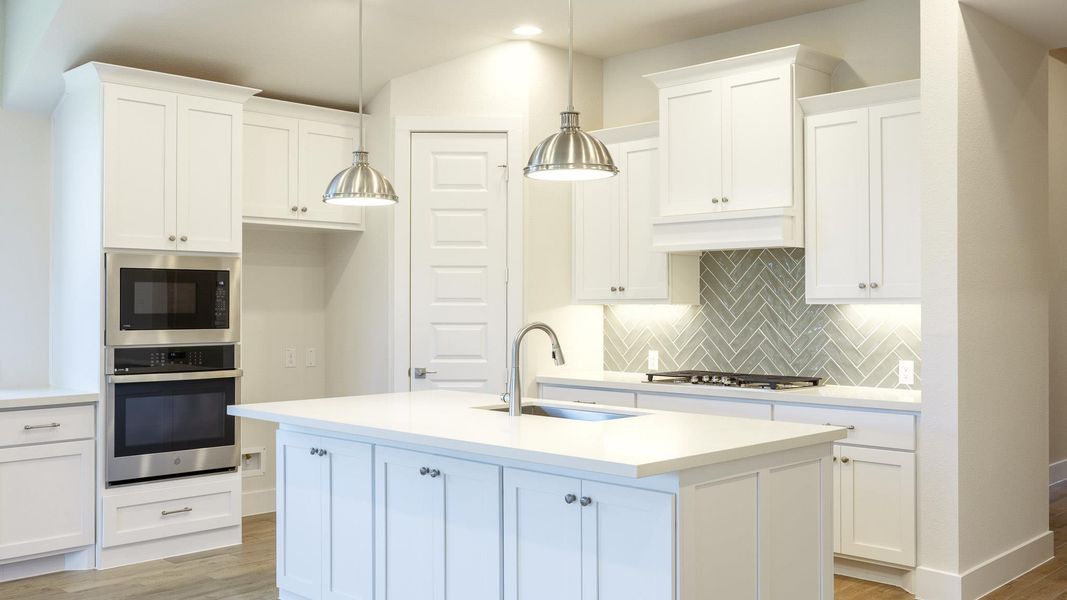 Kitchen with oven, light wood finished floors, white cabinets, and recessed lighting Kitchen with oven, light wood finished floors, white cabinets, and recessed lighting