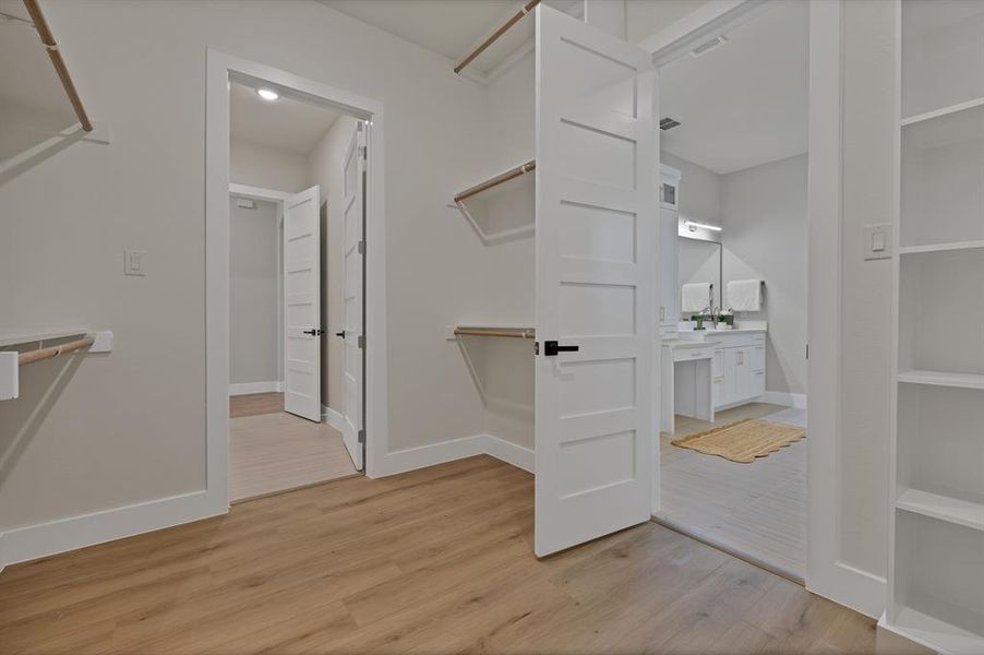 Walk in closet with light wood-style floors Walk in closet with light wood-style floors