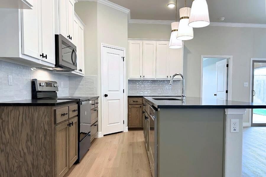 Kitchen featuring electric range, decorative light fixtures, light wood-type flooring, a center island with sink, and backsplash